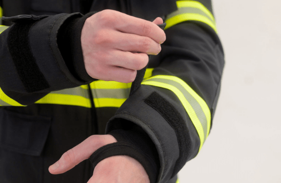 Hook-and-loop sleeve adjustment, inner moisture barrier, and fi re-retardant cuff with thumb hole.